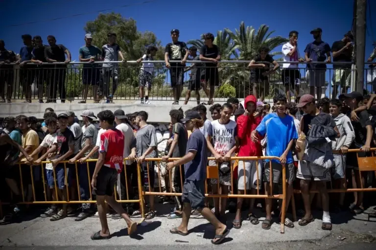 Dozens of Moroccans queue to receive food next to the mosque of the Muslim cemetery in Ceuta.
