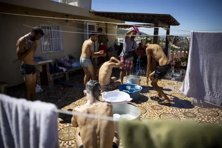 Several men clean themselves on the rooftop of the house.