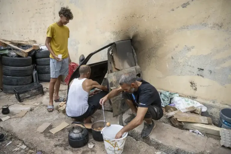 Adam (19) watches his father, Mohami (51), prepare the camp’s food.